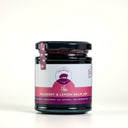 A glass jar of 'The Mulberry Pig' Mulberry and Lemon Balm Jam, featuring a white and magenta label with a black lid, set against a plain white background.