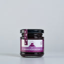 A glass jar of Spiced Plum Butter by The Mulberry Pig, featuring a black lid and a purple and white label, set against a plain light gray background.