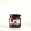 A glass jar of The Mulberry Pig Apple & Thyme Butter with a black lid and a purple and green label, set against a plain light gray background.