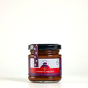 A picnic glass jar of The Mulberry Pig Tomato Relish with a black lid and a white, red, and purple label, set against a plain white background.
