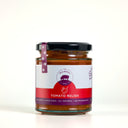 A glass jar of The Mulberry Pig Tomato Relish with a black lid and a white, red, and purple label, set against a plain white background.