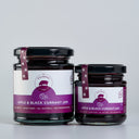 Two glass jars of The Mulberry Apple and Blackcurrant jam, one large and one small, with purple and white labels and black lids, set against a light gray background.