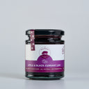 A glass jar of The Mulberry Pigs Apple & Black Currant Jam with a black lid and a purple label, set against a plain light gray background.