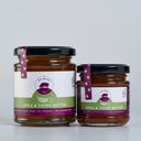 Two glass jars of The Mulberry Pig Apple & Thyme Butter, one large and one small, with black lids and white and green labels, set against a light gray background.