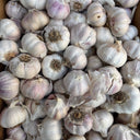 A close-up pile of  Australian whole garlic bulbs with pale off-white to light purple skins, filling the frame.