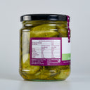 A glass jar of the mulberry pig bread and butter pickled cucumbers with a black lid, showing the back of the label with nutrition information. The jar is set against a clean, light gray background.
