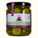 Jar of bread and butter pickles with a purple and white label on a white background