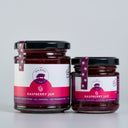 Two glass jars of Raspberry Jam  by The Mulberry Pig, one large and one small, with black lids and purple labels, set against a light gray background.