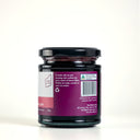 A glass jar of Mulberry and Lemon Balm Jam with a black lid and a purple label, photographed on a clean white background.
