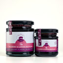 Two glass jars of The Mulberry Pig Mulberry & Lemon Balm Jam, one large and one small, with black lids and white and magenta labels, set against a clean white background.