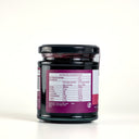 A glass jar of Mulberry and Lemon Balm Jam with a black lid, showing the back label with nutrition information, on a white background.
