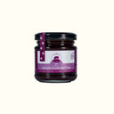 Jar of spiced plum butter with a purple label on a white background