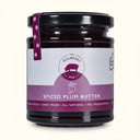 Jar of spiced plum butter with a purple label on a white background