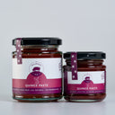 Two glass jars of Quince Paste by The Mulberry Pig, one large and one small, with black lids and purple labels, set against a light gray background.