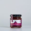 A glass jar of Quince Paste by The Mulberry Pig, featuring a black lid and a purple and white label, set against a plain light gray background.