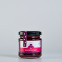 A glass jar of The Mulberry Pig Raspberry Jam with a black lid and a purple and white label, set against a plain light gray background.