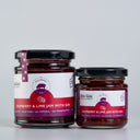 Two glass jars of Raspberry & Lime Jam with Gin from The Mulberry Pig, one large and one small, with white and purple labels and black lids, set against a light gray background.