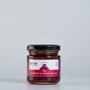 A glass jar of The Mulberry Pig, Raspberry & Lime Jam with Gin, featuring a black lid and a white and red label, set against a plain light gray background.