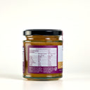 A glass jar of The Mulberry Pig apple pear and ginger chutney with a black lid and a purple label, photographed on a clean white background. The label includes a nutrition panel and product details