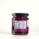 A glass jar of Beetroot Relish by The Mulberry Pig, featuring a black lid, a white and magenta label with the nutrition label on show, and a small hanging tag, set against a plain white background.