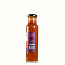 A glass bottle of The Mulberry Pig 
Handmade Chilli Garlic Sauce with Fenugreek, featuring a white and red label showing product description with a purple accent ribbon, set against a plain white background.