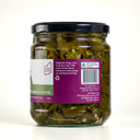 A glass jar of The Mulberry Pig Pickled Jalapeños with a black lid and a white, dark green, and purple label showing the blurb, set against a plain light grey background.