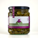 A glass jar of The Mulberry Pig Pickled Jalapeños with a black lid and a white, dark green, and purple label, set against a plain light grey background.