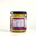 A glass jar of the mulberry pig lemon curd with a black lid and a purple label showing nutrition information, photographed on a clean white background.