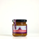 A Picnic size glass jar of The Mulberry Pig Peach, Chilli and Black Pepper Chutney on a clean white background. The jar has a black lid, a purple and white label, and a purple seal ribbon, with visible chunks of reddish-brown chutney inside.