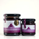 Two glass jars of  Spiced Plum Butter by The Mulberry Pig, one large and one small, with black lids and purple labels, set against a light gray background.