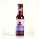 A 150g glass bottle of The Mulberry Pig Salted Plum & Black Pepper Sauce, a vegan and gluten-free Worcestershire-style sauce, with a black cap, purple ribbon neck tag and a white and lavender label reading Small Batch, Hand Made, All Natural, No Preservatives, set against a plain cream background.