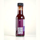 Side of a bottle of The Mulberry Pig Salted Plum & Black Pepper Worcestershire Sauce showing the ingredients list, with fermented plums (44%), and the nutrition information panel, labelled gluten free and vegan, set against a plain cream background.