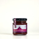 A glass jar of Quince Paste by The Mulberry Pig, featuring a black lid and a purple and white label, set against a plain light cream background.