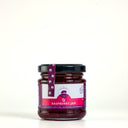A glass jar of The Mulberry Pig Raspberry Jam with a black lid and a purple and white label, set against a plain light gray background.