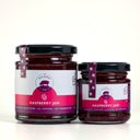 Two glass jars of Raspberry Jam  by The Mulberry Pig, one large and one small, with black lids and purple labels, set against a light gray background.