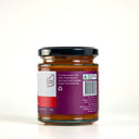 A glass jar of The Mulberry Pig Tomato Relish with a black lid and a white, red, and purple label showing the description
, set against a plain white background.